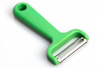 Green vegetable peeler with stainless steel blade isolated on white background. Kitchen utensils and equipment