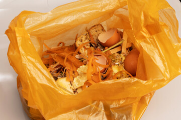 Bio organic trash sorted in yellow plastic bag for composting or recycling isolated on white background. 