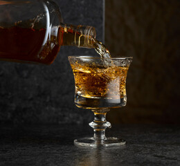 Pouring strong alcoholic drink from a bottle into a glass.