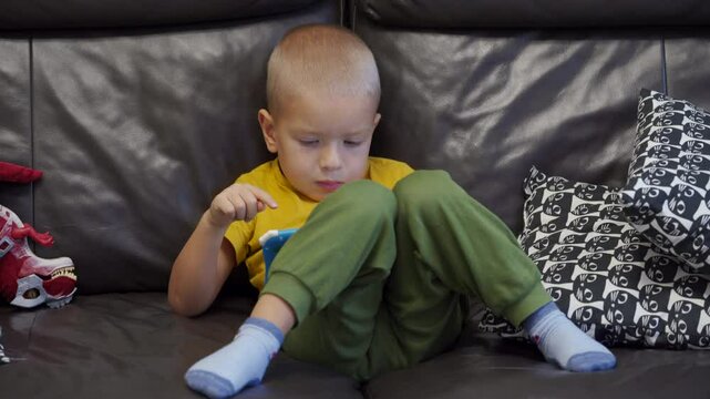 Child sitting on sofa and playing on tablet for kids. Little boy's face smiling while playing.