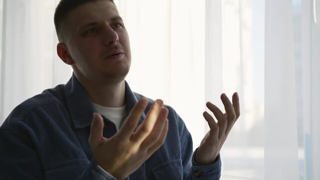 Serious man talking about business.
A man is talking and gesticulating with his hands.
Hand gestures during a conversation.
A man in a blue shirt communicates with his interlocutor