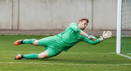 Professional soccer goalkeeper in action, diving save on the field, perfect for sports posters and athletic promotions