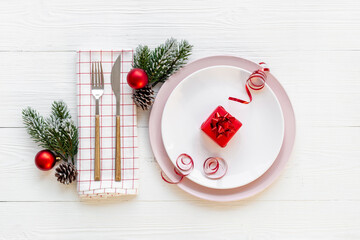 Red colored table setting flatlay for Christmas and New Year Eve. Empty plate with cutlery and decoration, top view