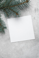 Blank paper flyer card mockup with fir tree branch on grey concrete background, copy space