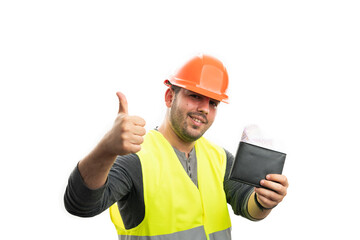 Happy cheerful constructor man wearing orange helmet and fluorescent vest holding leather wallet