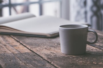 a white coffee mug sits on a wooden table.