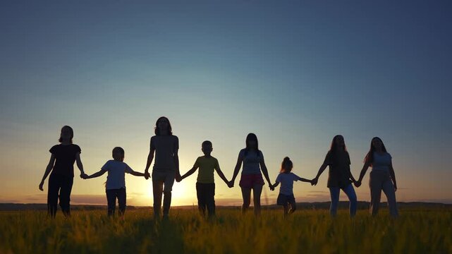 big community family in the park. silhouette of a large group of people holding hands walking at sunset in a park in nature in summer. happy family lifestyle kid dream concept. big community