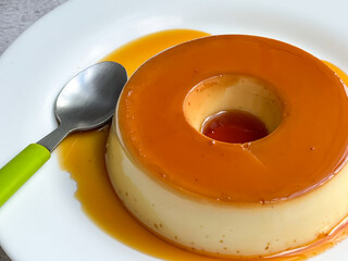 Smooth caramel pudding with a glossy finish on a white plate.