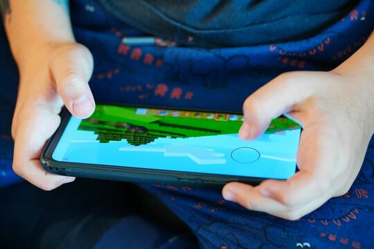 Young boy playing Minecraft on a smartphone