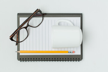 Notepad with pencil, glasses and cup of coffee on the table
