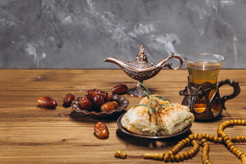 Ramadan concept, cup of tea, plate of sweet dates and baklava, copy space