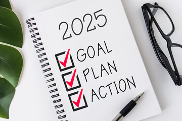 2025 Goal, Plan, Action checklist text on note pad with glasses and pen.