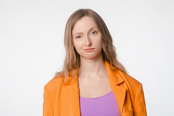 bored or dissatisfied young woman in an orange blazer standing against a white background, expressing disinterest, frustration, or lack of enthusiasm in everyday scenarios