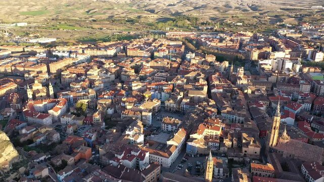 Picturesque drone view of Calatayud cityscape in spring in valley of Iberian mountain area overlooking brownish tiled roofs of residential buildings, Spain