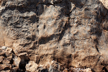 Cracked rock texture in sunny day with contrast background.