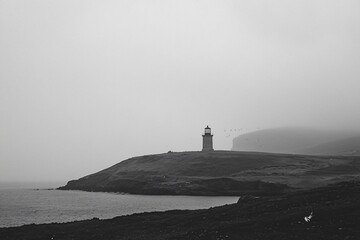 Misty Lighthouse Overlooking a Serene Coastline in Black and White