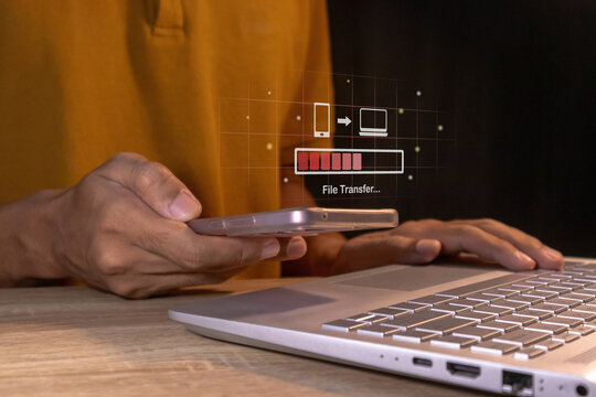 Backup, copy file and media or exchange data concept. Man transfer files from mobile phone to laptop.