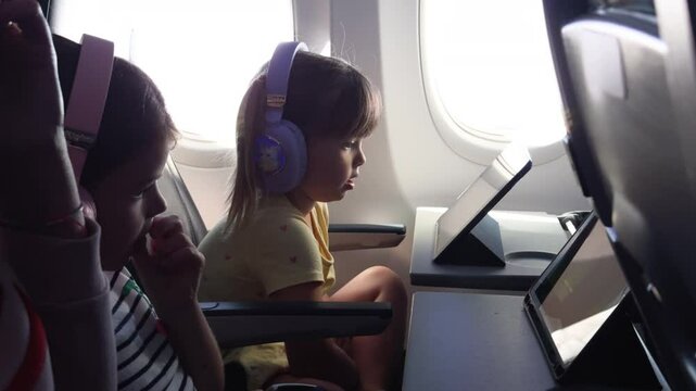 4K: Cute Young girl using digital tablet whilst flying onboard an Airplane or Plane. Stock Video Clip Footage