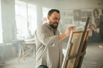 Male artist painting on canvas in a sunlit art studio