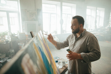 Focused male painter working on a new artwork