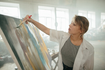 Young woman experimenting with paint techniques on her artwork