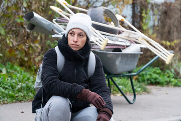 woman sitting on curb in black jacket, poverty, poor people collecting scrap metal, wheelbarrow, garbage collection, europe, america, usa, russia, unhappy woman, alcoholism