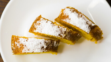 Delicious pumpkin cupcake cut into pieces on a white plate on a dark wooden table