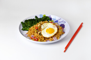 Fried noodles with sunny side up egg and mixed vegetables on a plate