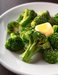 Steamed broccoli on a white plate with a few drops of melted butter