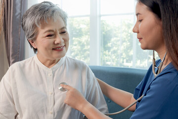 Happy Asian mature receiving checkup and advice from medical staff. Beautiful female doctor using...