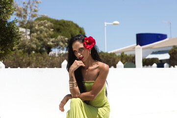 beautiful young brunette woman with green eyes and green dress wearing a hibiscus flower on her...