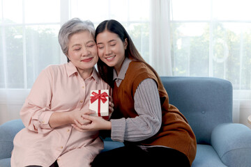 Asian senior grandma received a gift box present from granddaughter. Happy elderly mature woman...