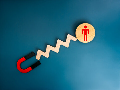 Business digital marketing, attract leads and customers concept. A Magnet attracts to selected person icon on round wooden on blue background. Business team building, recruitment, hiring concepts.