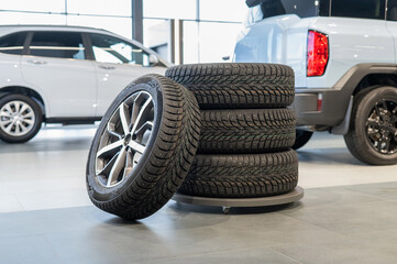 New wheels with studded tires against the background of new cars. 