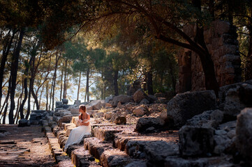 Young beautiful woman wering white dress at antique ruin