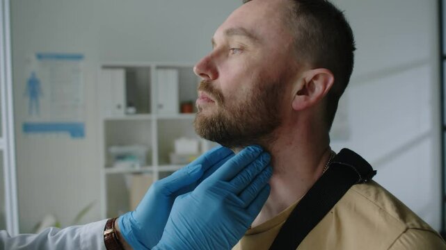 Close-up shot of unrecognizable doctor in medical gloves performing general physical examination on his soldier patient in military clothing