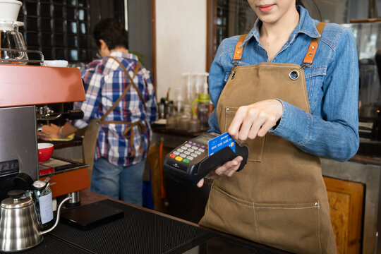 Close-up baristas or cashier worker hold payment machine accept credit card cashless transactions from customers, Smart business owner hand payment scanner to customers in cafe shop to pay for coffee