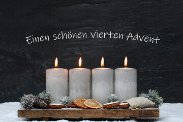 Vierter Advent: Adventsdekoration
 mit grauen brennenden Kerzen, Weihnachtsschmuck und dem Text...