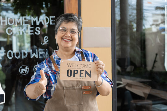Asian elderly, senior, pensioner, female open cafe restaurant small business at home town after retirement, healthy strong 60s woman happy lifestyle wearing apron working as barista waitress worker