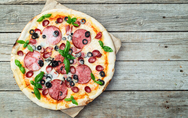 Pizza with mozzarella cheese , salami sausages , olives , and basil