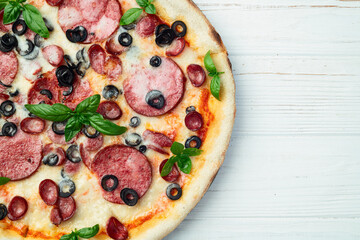 Pizza with mozzarella cheese , salami sausages , olives , and basil