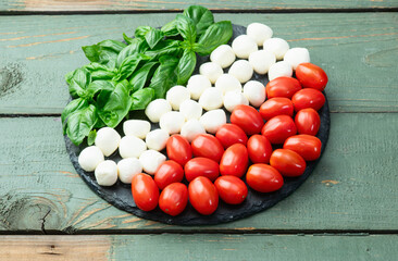 Basil leaves , cherry tomatoes and mozzarella cheese . In form italian flag food photography