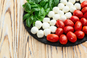 Basil leaves , cherry tomatoes and mozzarella cheese . In form italian flag food photography
