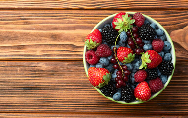 Mix of ripe colorful berries in bowl photography . Blueberry , strawberry , raspberry , blackberry and red currant . Top view