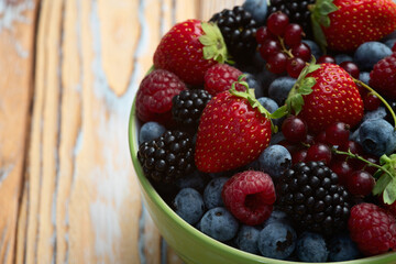 Mix of ripe colorful berries in bowl photography . Blueberry , strawberry , raspberry , blackberry and red currant . Top view