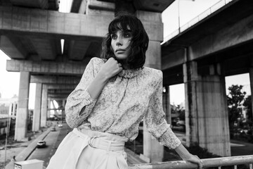 Black and white photo of a girl in classic clothes posing on the streets of Bangkok.