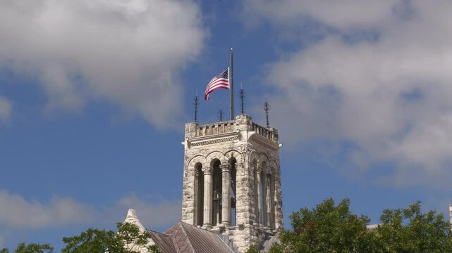 American flag on top of Comal County Courthouse in New Braunfels, Texas with sky background