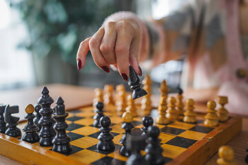 Close-up of woman hand move chess piece in strategic board game