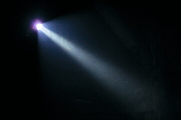 the beam of light from the headlamp illuminates smoke and dust particles in the dark