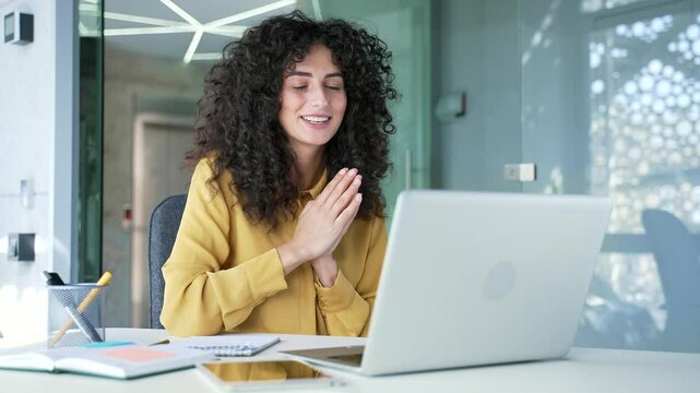 Young adult businesswoman talking on a video call using laptop sitting at workplace in business office. A female manager has a remote business meeting. Coach speaks at an online course or training